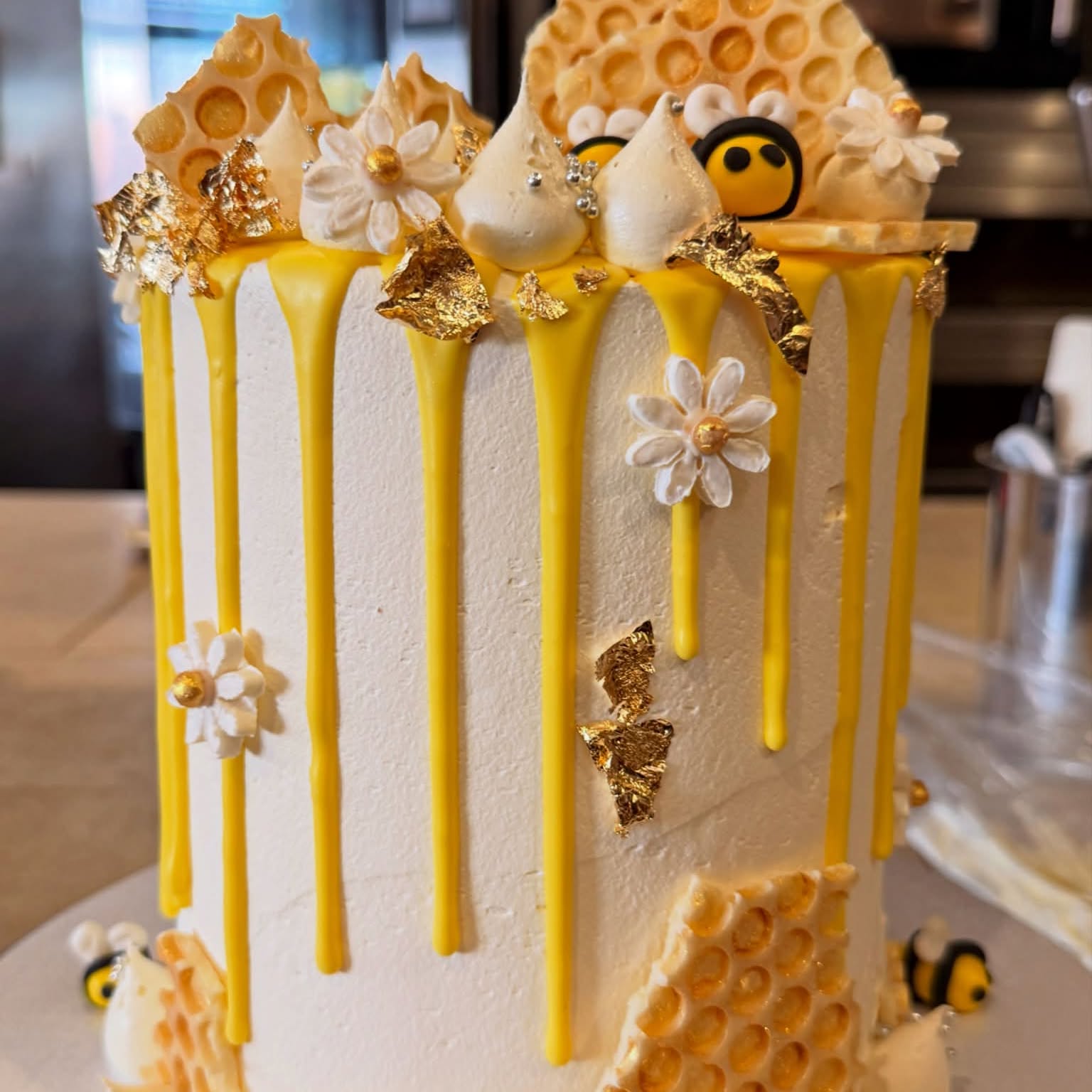 Honeycomb and bee drip cake with gold leaf and daisy decorations