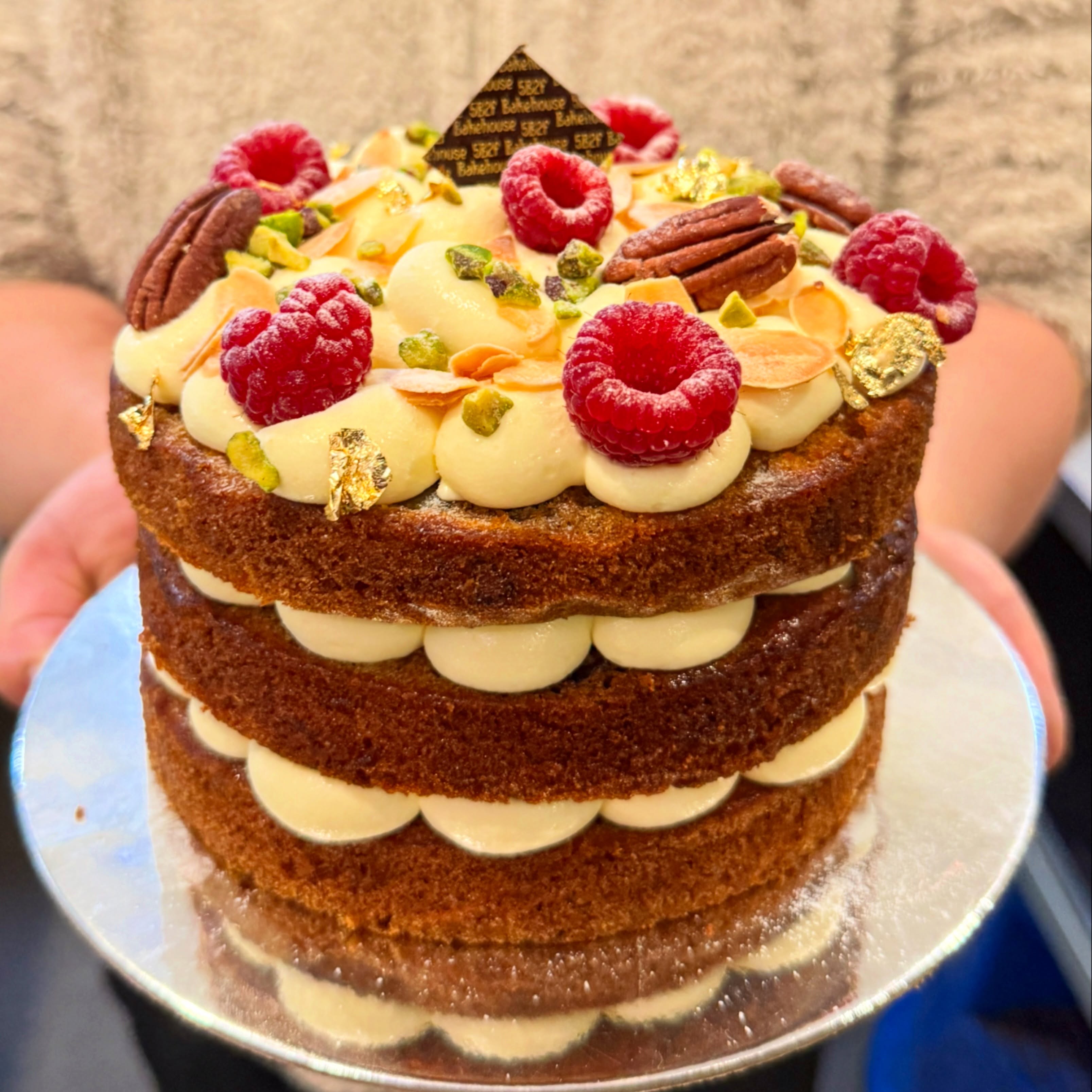 Naked carrot cake with pecans, raspberries and gold leaf
