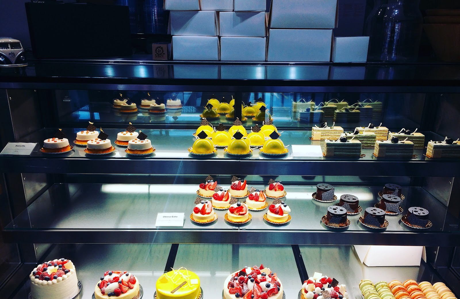 The cabinet on an earlier day: mini cheesecakes, glazed domes, macarons and whole cakes